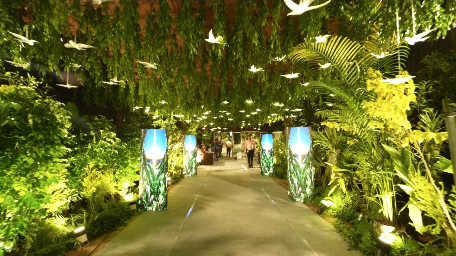 A walkway of greenery and suspended paper birds at the launch